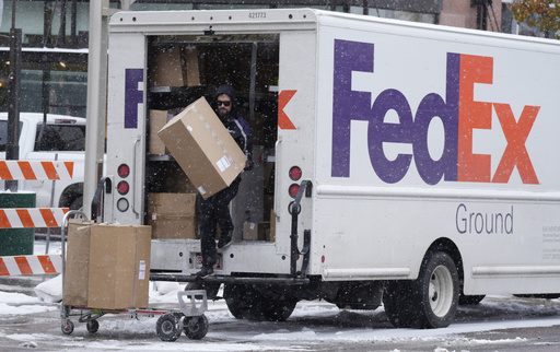 A FedEx delivery person carries a package 