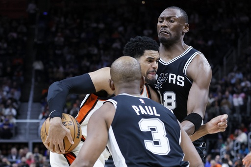 Detroit Pistons forward Tobias Harris, center, drives to the basket between San Antonio Spurs center Bismack Biyombo, right, and guard Chris Paul (3) during the first half of an NBA basketball game Tuesday, March 25, 2025, in Detroit. (AP Photo/Duane Burleson)